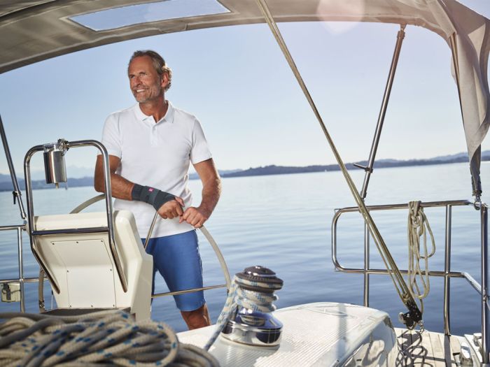 A man on a sailboat wears a wrist brace, showcasing orthopedic support products from medical equipment supplier in Ottawa.